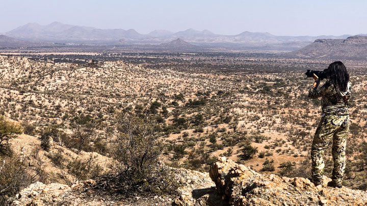 female hunter looking over arid land from high vantage