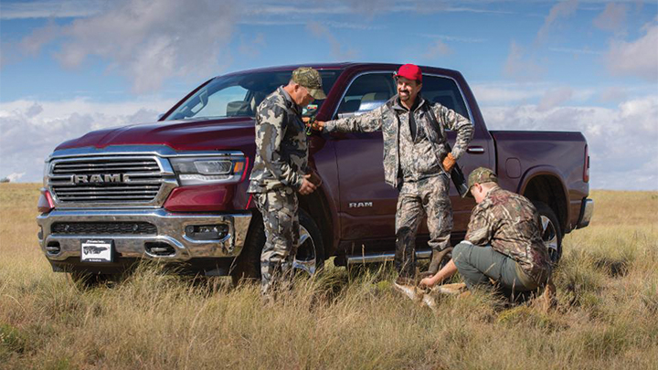 hunters gather at pickup truck in field