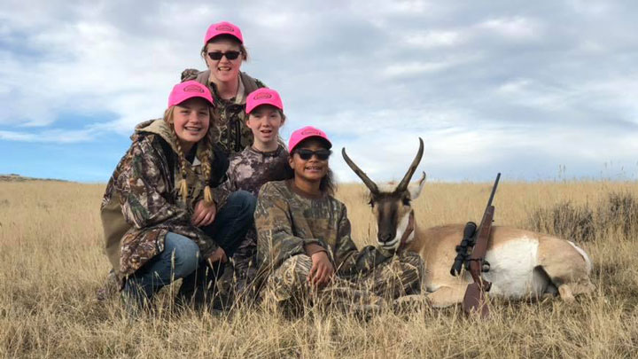 a woman and three girls pose with a pronghorn antelope one of the girls hunted and killed