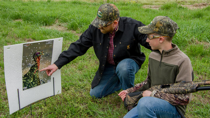 an adult instructs a young boy how to pattern a turkey-hunting shotgun