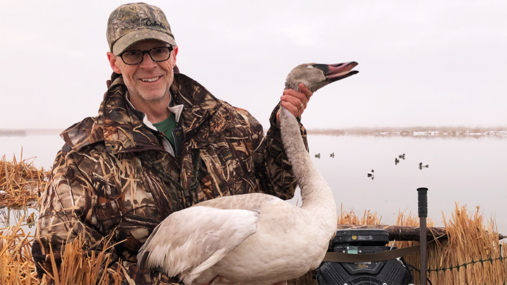 waterfowl hunter poses with a tundra swan taken on the great salt lake