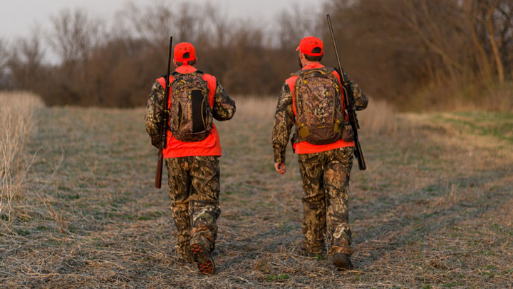 two hunters walk through the outdoors