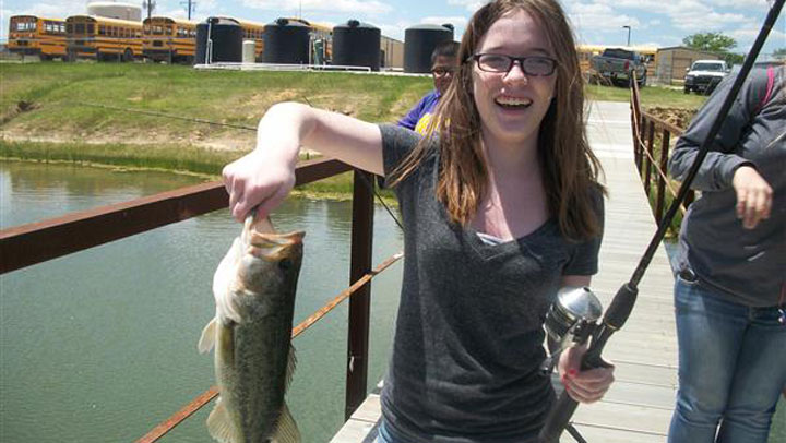 a young girl proudly shows off the fish she caught in an outdoors tomorrow foundation outdoor class