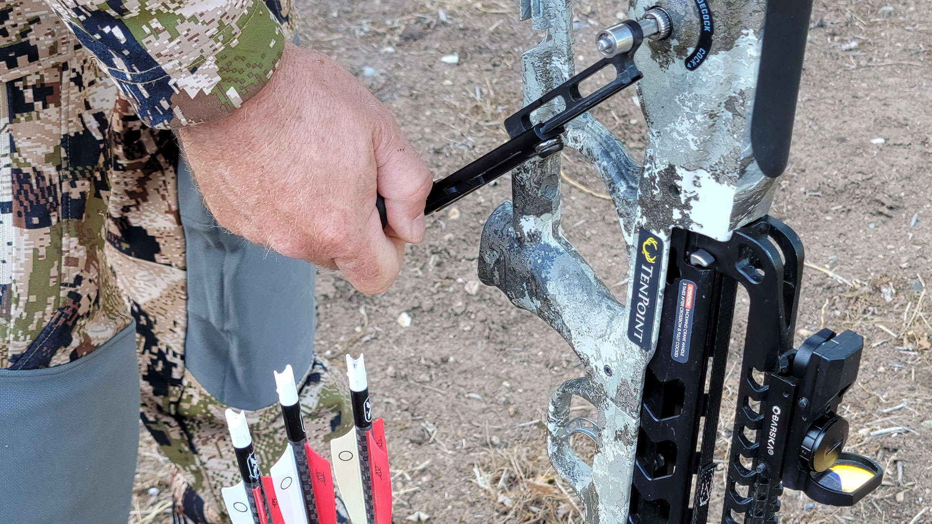 hunter cocks crossbow with cocking device