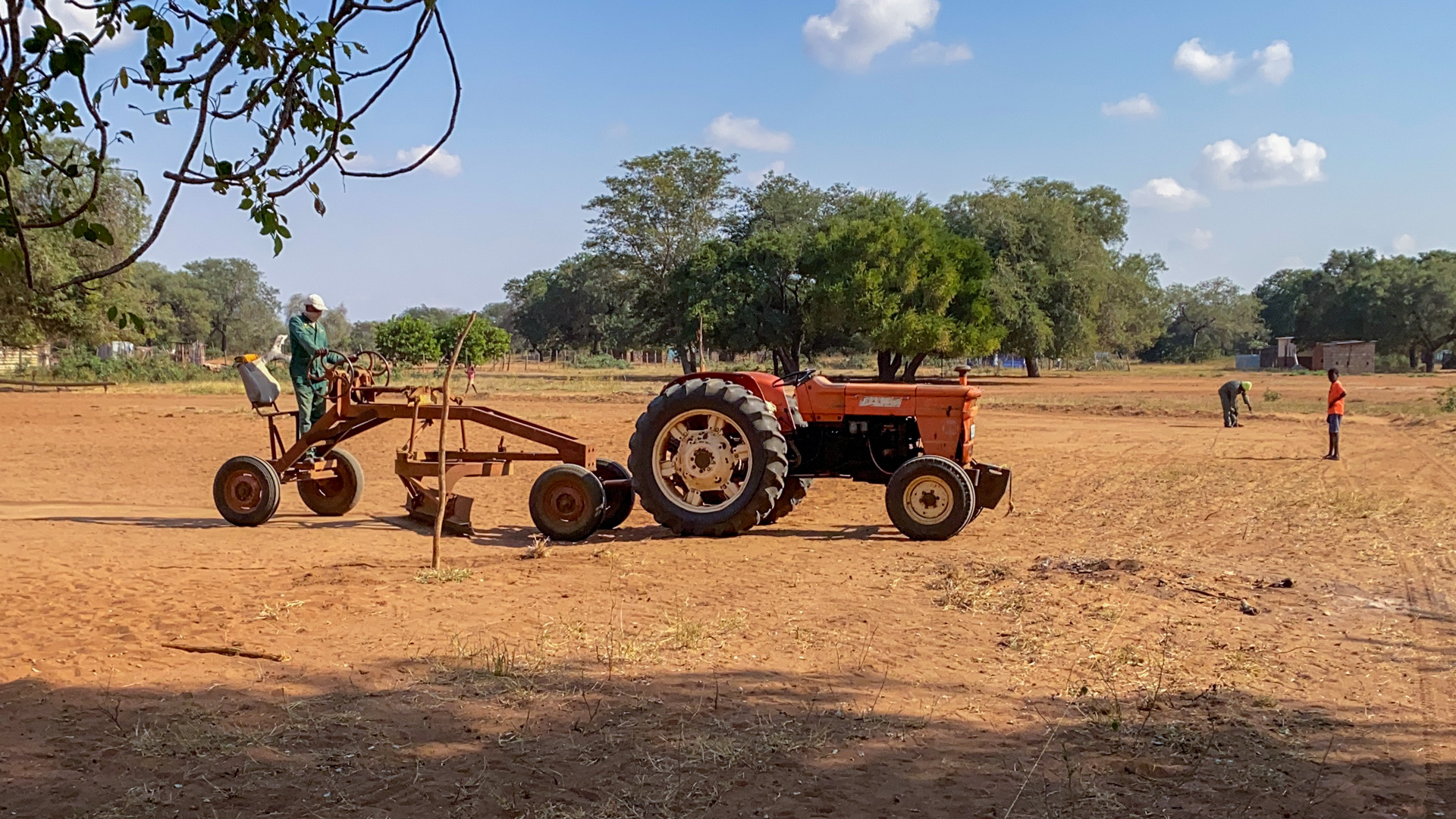 a farmer grades the new soccer field with a tractor